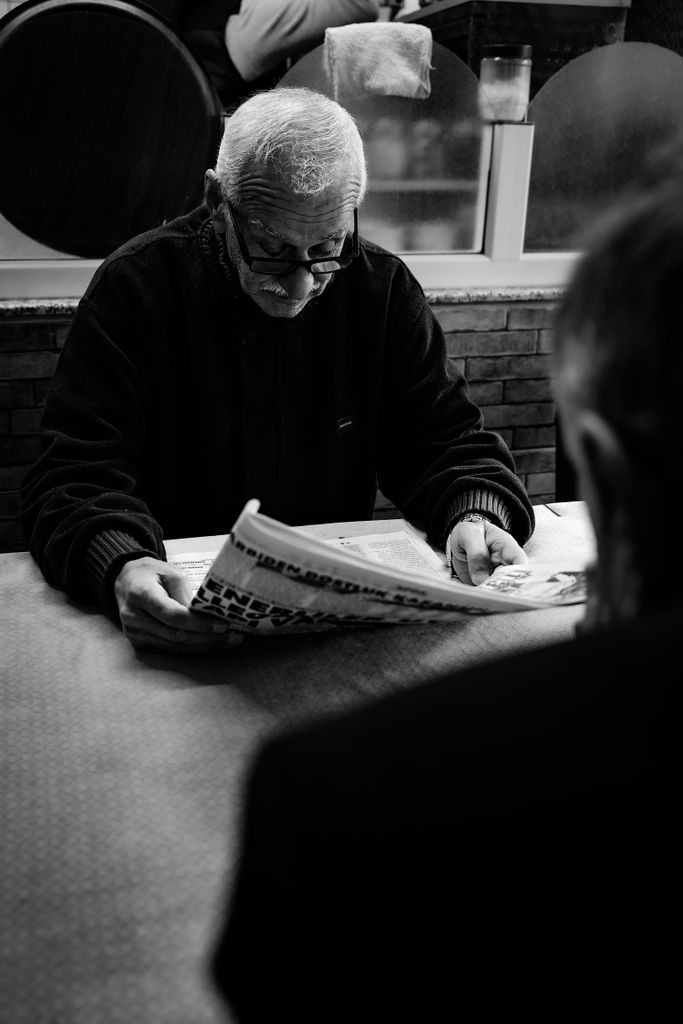 Intimate black and white portrait of an older man reading in an Istanbul cafe.